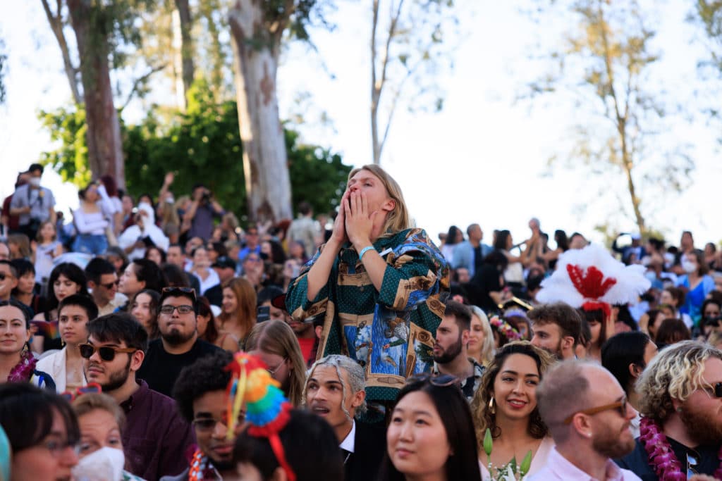A crowd shot from CalArts graduation, with one student standing in the crowd.