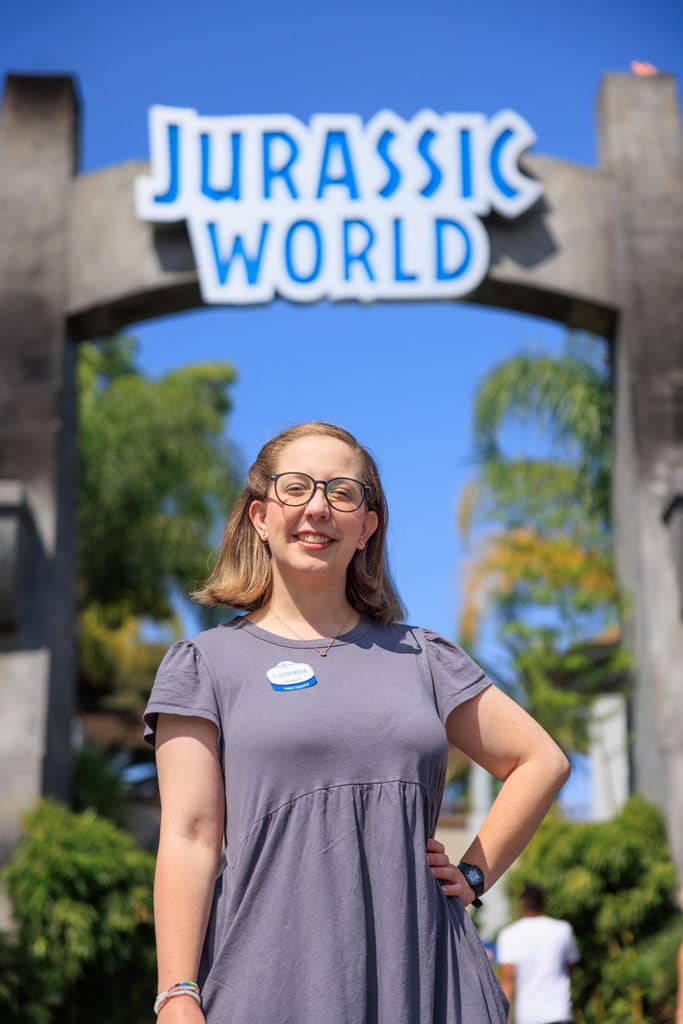 A woman stands under a Jurassic World sign at the theme park