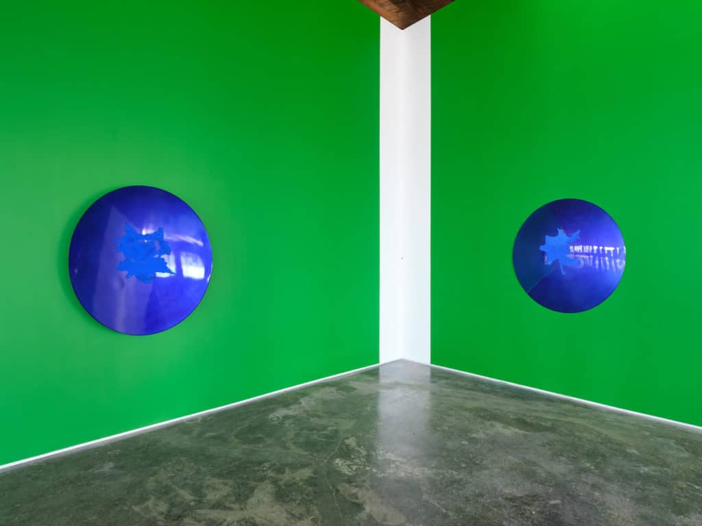 two green walls with two blue reflective circles separated by a white line in the corner