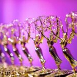 Gold Emmy Statues lined up against a purple backdrop
