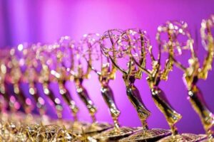 Gold Emmy Statues lined up against a purple backdrop
