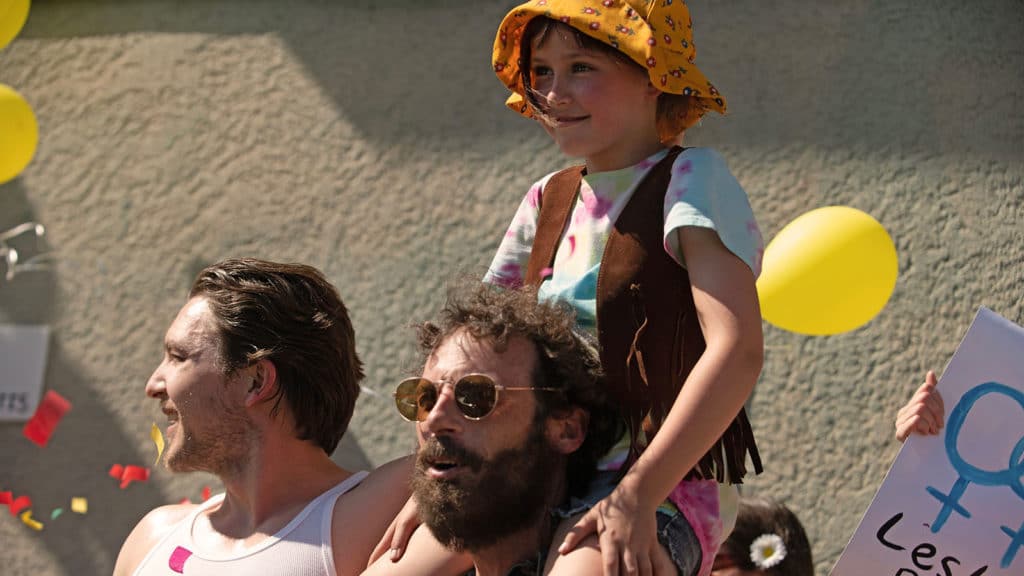 Child sits on shoulders of man in sunglasses