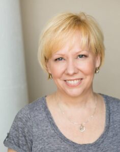 Artist smiling at camera, wearing heather gray T-shirt