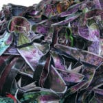 Mixed media assemblage of materials resembling purple and green flowers.