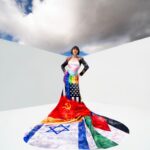 Full view of artist in the Slava Culture War gown against white background and cloudy sky