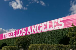 Pink Frieze Los Angeles banner atop hedges