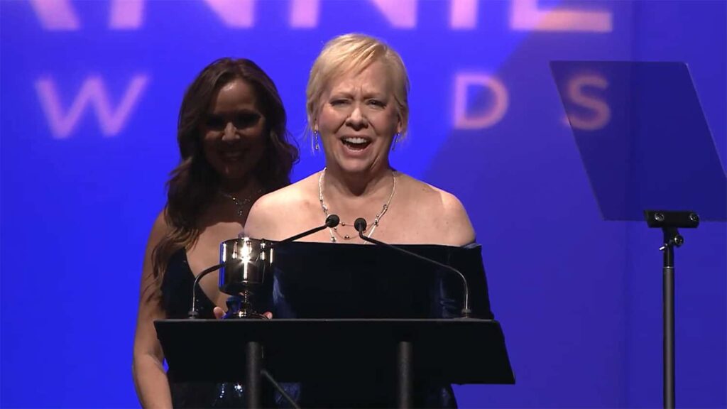 Mindy Johnson smiling at podium with zoetrope trophy