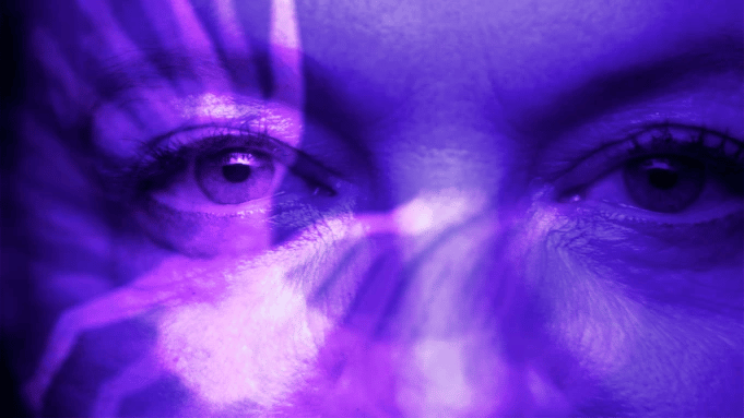 An ethereal image of a woman's eyes bathed in purple.