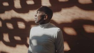 Artist Charles Gaines standing against shadows of large chainlinks