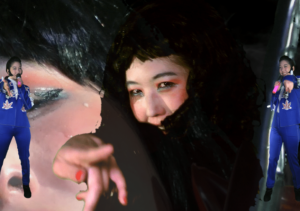 A still image from a film where a woman's face is seen up close with three additional images of herself, two of them are dressed like Elvis in a blue suit.