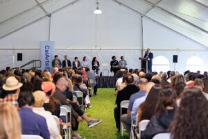 Ravi Rajan at a podium with administration members on stage address a tent of parents and accepted students.