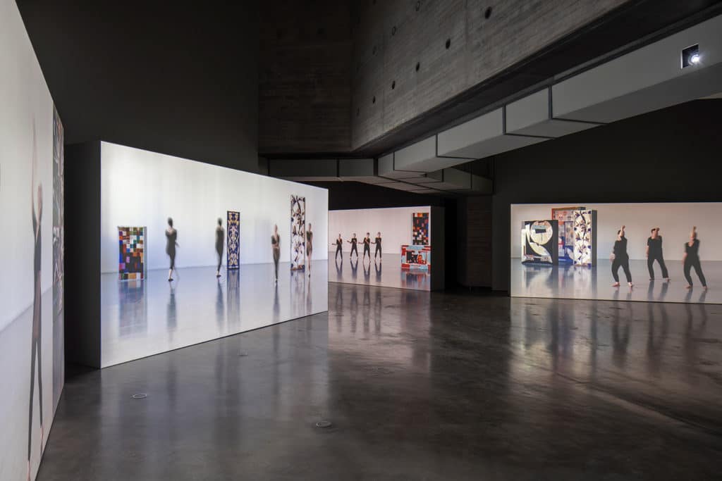Videos of dancers in various movements and poses projected against four gallery walls