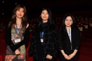 Three women at the CalArts 2023 Producers' Show wear lanyards inside the David Geffen Theater at the Academy Museum in Los Angeles.