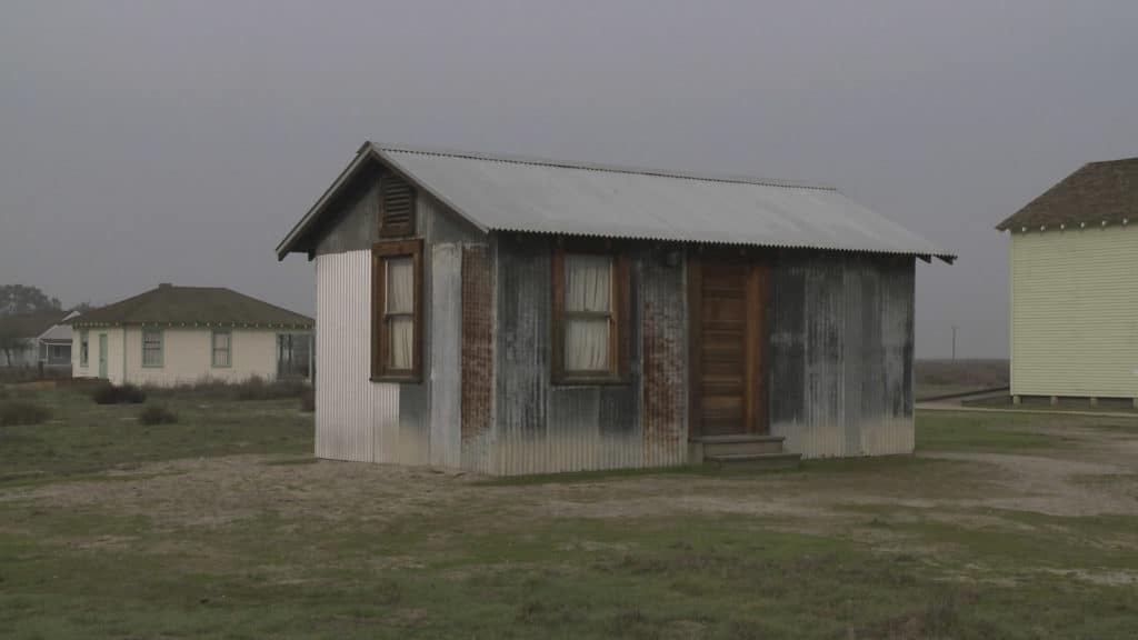 Faded shack on grassy plain and overcast sky