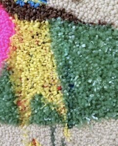 Closeup of densely tufted needlepoint in different colors and textures