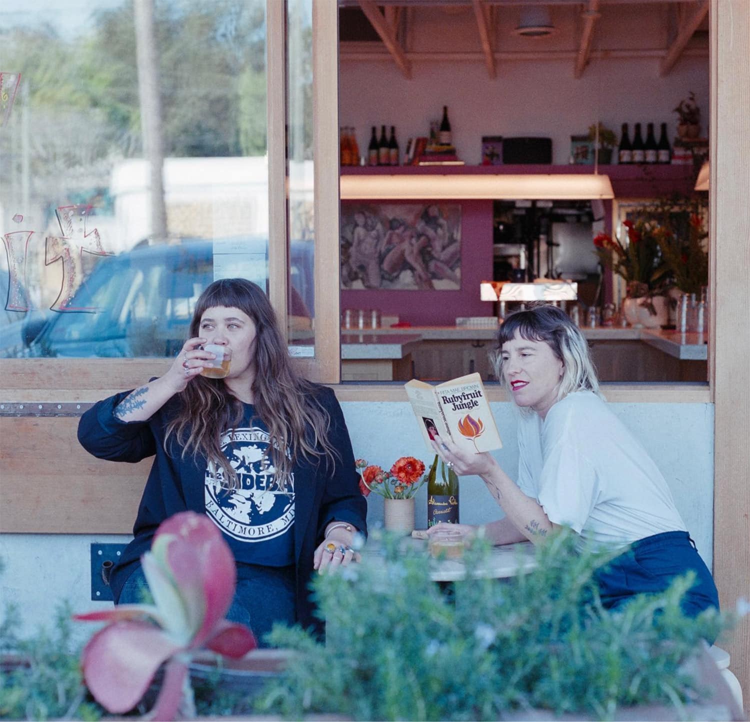 Two women sitting outside drinking wine.