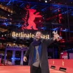 Director Nelson Carlos De Los Santos Arias holds up his Silver Bear at the Berlinale in front of the festival's venue.
