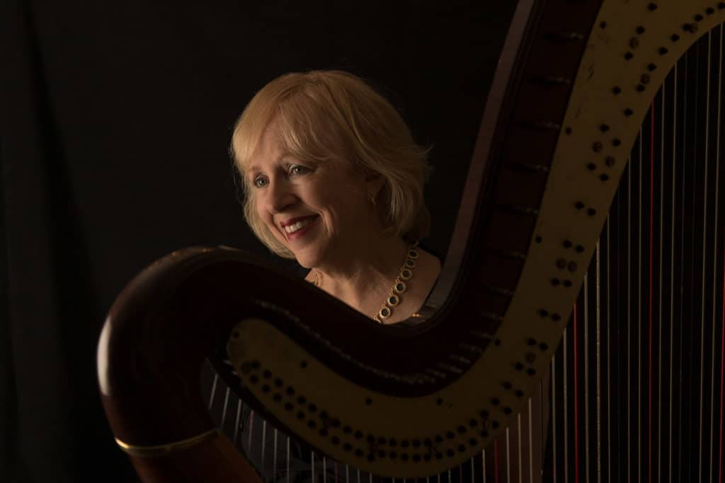 Anne LeBaron smiling while playing harp