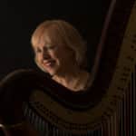 Anne LeBaron smiling while playing harp