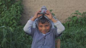 Young boy smiles while pulling a blue mask off his face