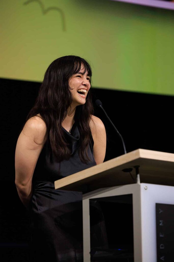 Shea Territo smiles while speaking at podium.