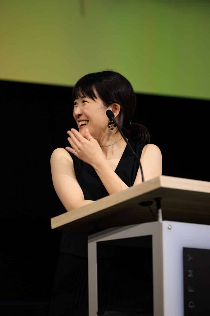 Sumin Ha smiling at podium while looking to the left.