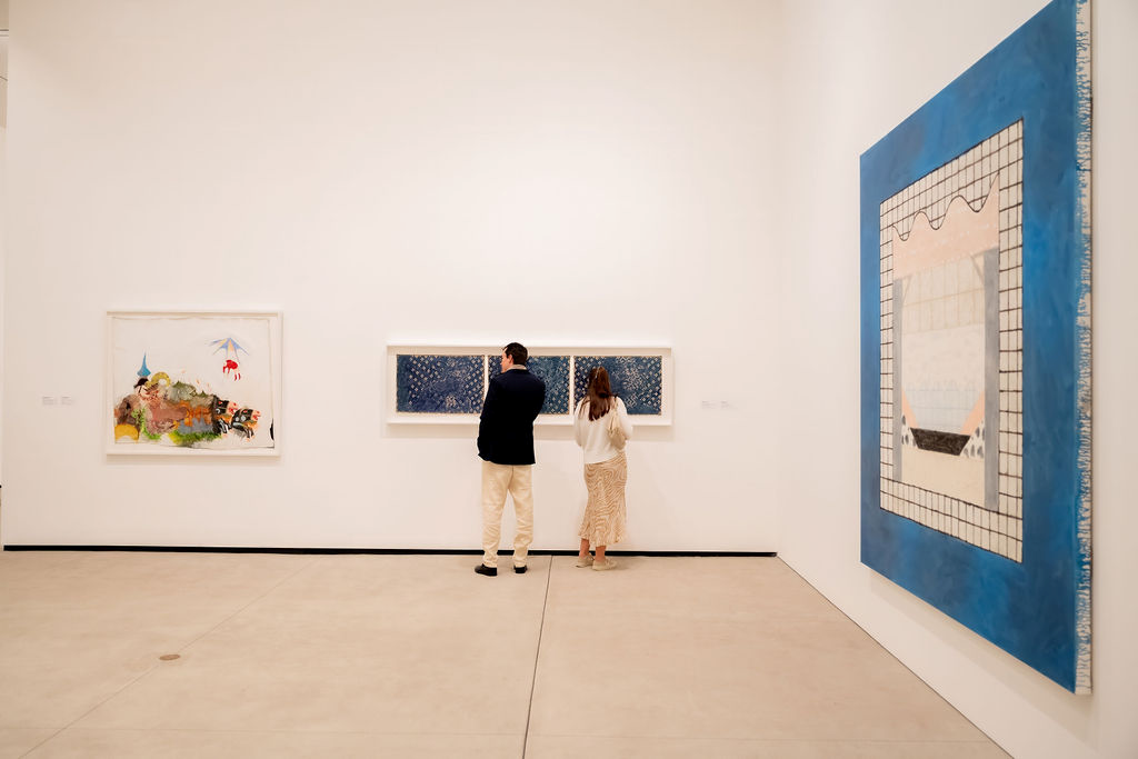 Back view of two people looking at artwork on gallery walls