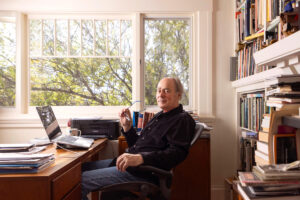 Tom Lawson looks at the camera from his desk in front of a window.