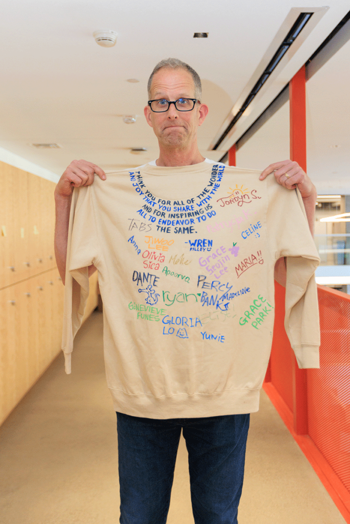 Docter holding up a signed crew neck sweater.