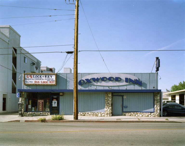 An exterior daytime shot of a one-story building called the Oxwood Inn. A telephone pole sits in front of the bar.