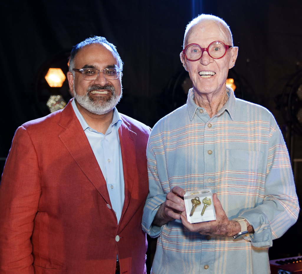 Ravi Rajan and Bob Fitzpatrick stand with Bob holding an award. 