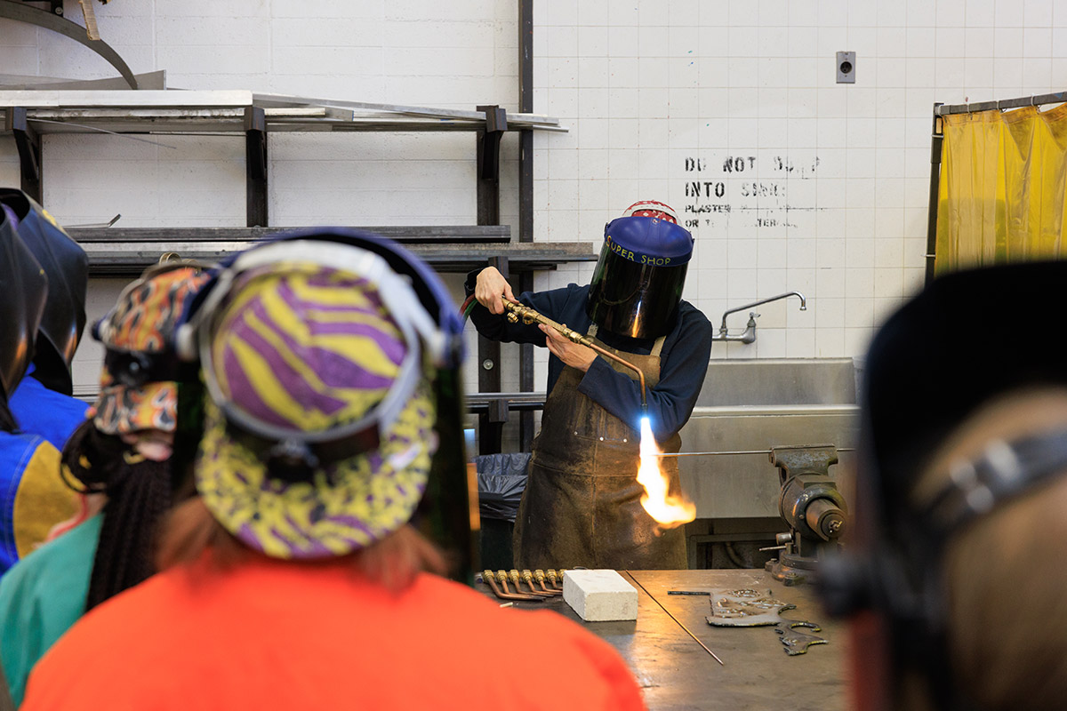 Inside a workshop a person is wearing a protective helmet and apparel while welding