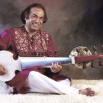 Aashish Khan smiling while playing sarod.