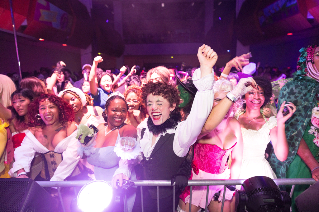 Costumed students cheering and dancing behind stage railing