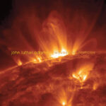 Solar flares with "John Luther Adams Waves and Particles" superimposed in orange text