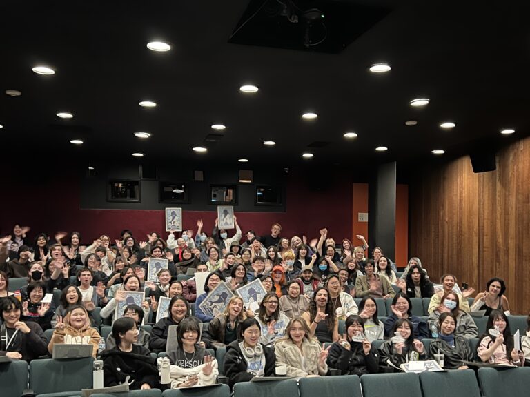 Students sitting in the Bijou theater, with several holding up Moana 2 posters