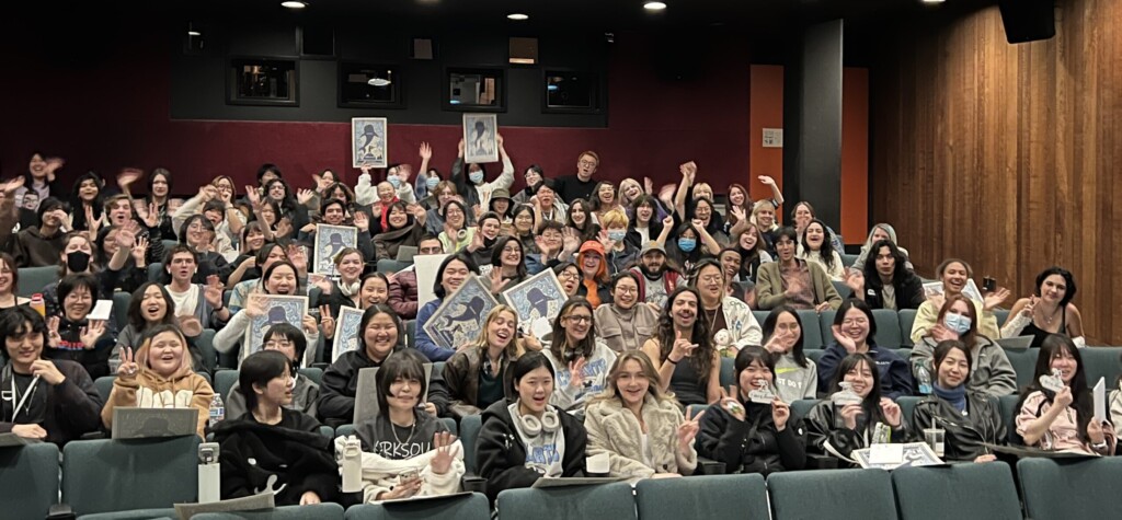 Students sitting in the Bijou theater, with several holding up Moana 2 posters