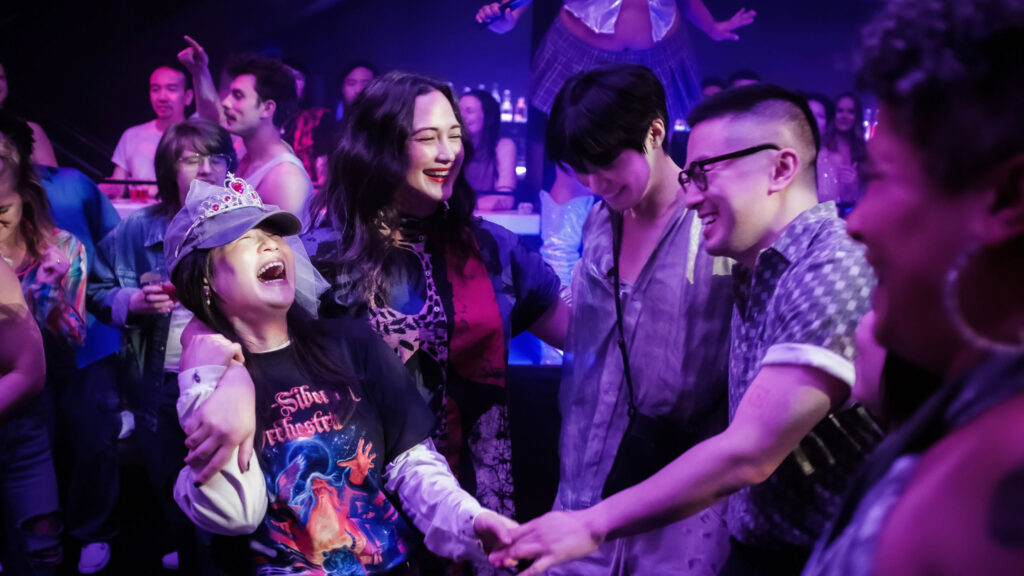 Four friends smiling as they hold hands in a circle at a bar.