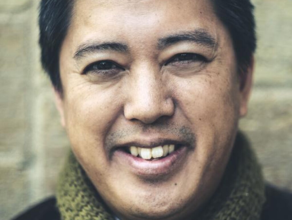 Headshot of Chris Santiago wearing a green scarf