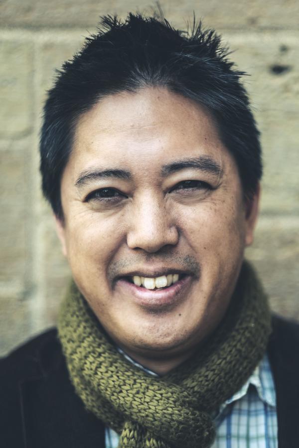 Headshot of Chris Santiago wearing a green scarf