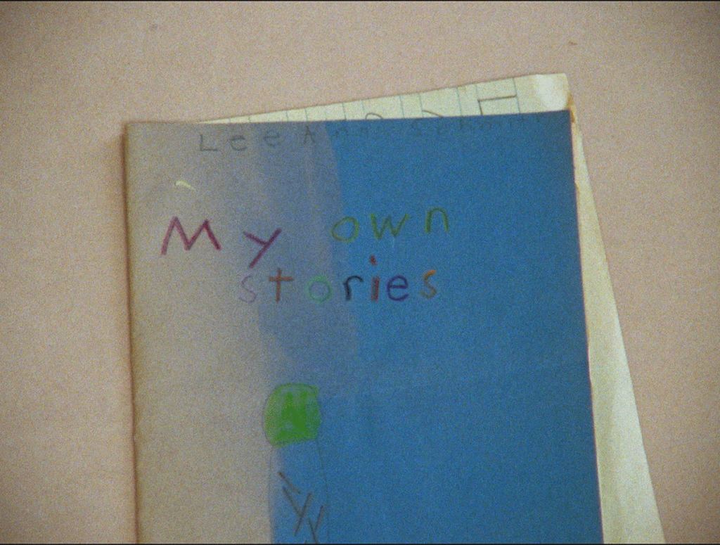 Faded blue page with multicolored title "My own stories" with yellowed line paper peeking out underneath