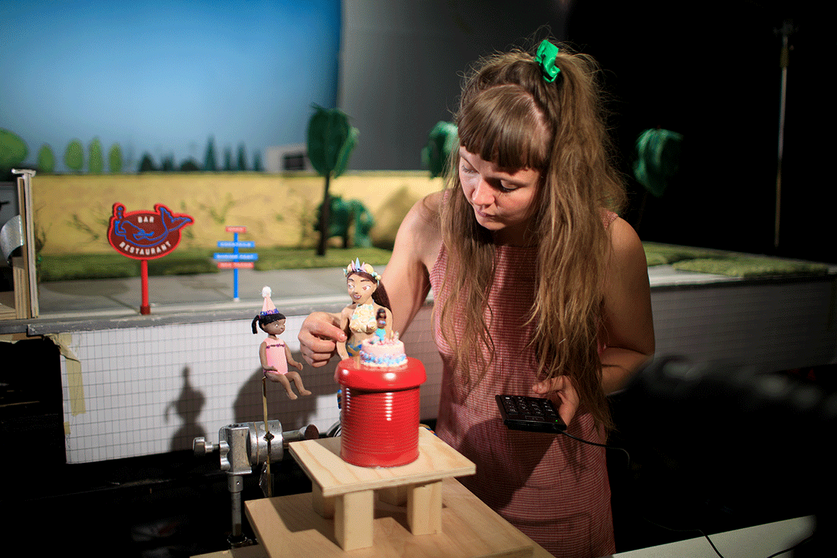 Cissi Efraimsson adjusting a claymation mermaid on a set designed like a waterpark