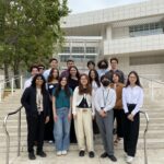 Group shot of 16 students standing at the steps leading to North Pavilion at the Getty Museum