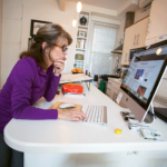 Ann Telnaes reading digital news on a monitor