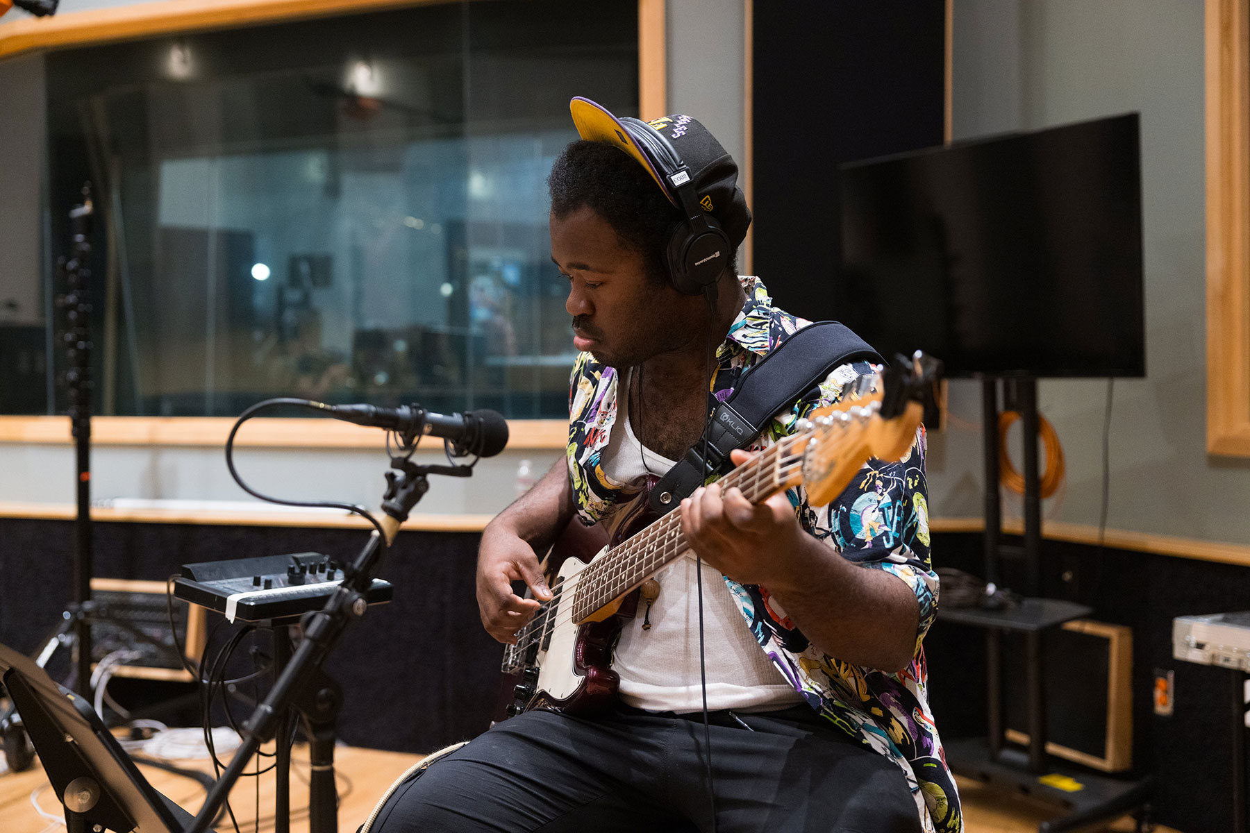 a bass player sits in a recording studio intently reading sheet music