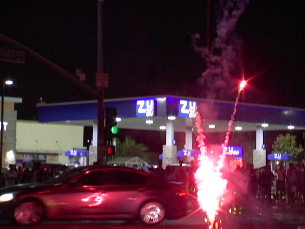 Night scene with fireworks in front of a gas station.