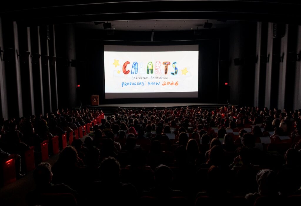 A dark theater filled with people with CalArts Character Animation Producers' Show on the screen.