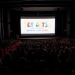 A dark theater filled with people with CalArts Character Animation Producers' Show on the screen.