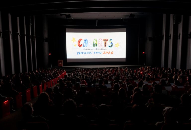 A dark theater filled with people with CalArts Character Animation Producers' Show on the screen.