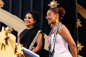 Two women at a podium, smiling at an unseen audience.